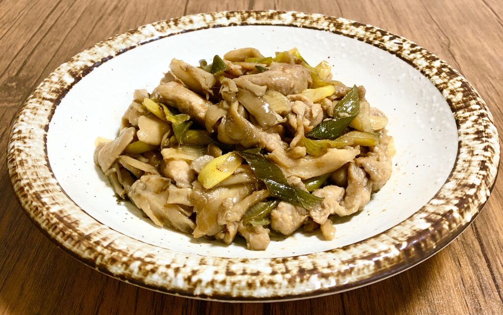 茶色の縁の深皿に盛り付けた豚肉と舞茸のバタポン炒め