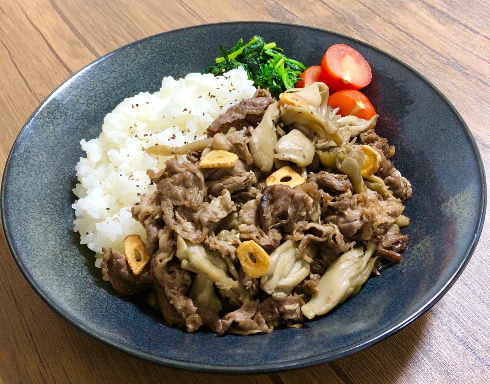 黒の深皿に盛り付けた牛こま肉と舞茸のガーリックバター醤油炒め
